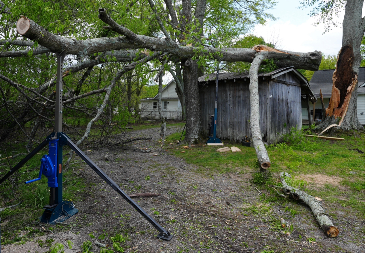 Fallen tree on a structure lifted and support by two Emergency Tree Jacks.